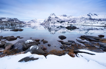 Wall Mural - Mountain ridge and ice on the frozen lake surface. Natural landscape on the Lofoten islands, Norway. Water and mountains during sunset. Travel - image