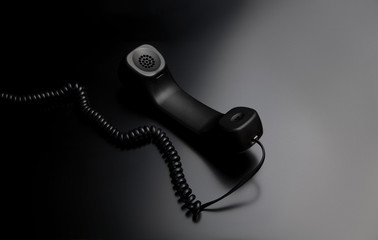 modern telephone receiver on dark back. concept technical support by phone. waiting for an answer. n