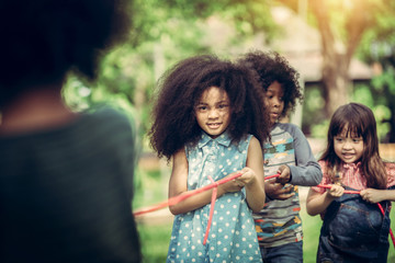 Happy children playing tug of war in the park.