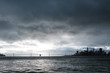 San Francisco skyline and Bay Bridge with dark clouds above shot from the Alcatraz