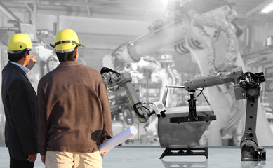 production engineer working with automate wireless Robot arm in smart factory background. Mixed media of welding robot in the automotive parts industry