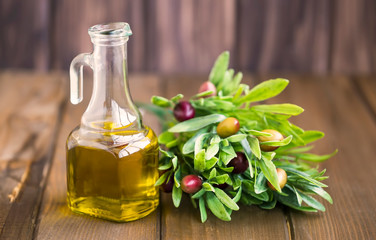 Wall Mural - Organic olive oil bottle with olives branch on rustic wooden background, fresh healthy raw mediterranean ingredient