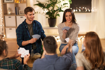 Wall Mural - friendship, leisure and entertainment concept - happy friends with non-alcoholic beer playing cards game at home in evening