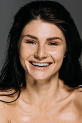 Wall Mural - portrait of happy girl with freckles on face laughing isolated on grey
