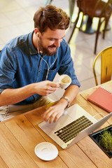 Wall Mural - Man listens music on laptop in cafe