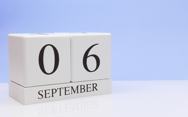 September 06st. Day 6 of month, daily calendar on white table with reflection, with light blue background. Autumn time, empty space for text