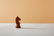 © LIGHTFIELD STUDIOS - wooden knight piece on white table and beige background