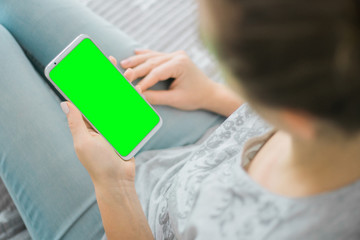 Wall Mural - Green screen smartphone. Woman's hands holding mobile phone Mockup image. chroma key. close up.