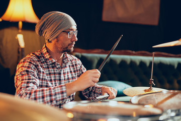 Poster - Caucasian drummer playing his instrument while sitting in home studio.