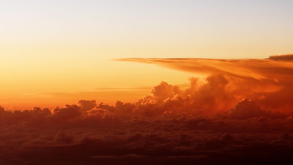 Wall Mural -  footage of beautiful sunset clouds from airplane window. Bright intense orange cloudscape view from above. Flight through moving yellow clouds in the evening sunshine.