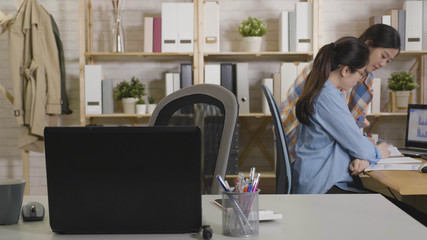 Wall Mural - young girl freelancer leave her seat workplace to colleague. women in casual suit teamwork partner discussing project in morden office in morning. ladies looking at paper documents on desk.