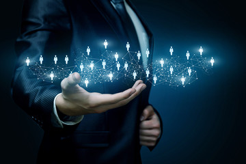 a businessman holding a system of wireless connections with human figures models.