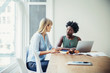© Cavan Images - Two businesswomen talking at desk