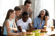 © fizkes - Smiling African American man showing funny video to friends