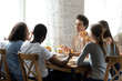 © fizkes - Multiracial friends having conversation and eating pizza in cafe