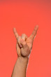 © Niko_Dali - Close-up of a man's hand with a goat's sign isolated on a red background