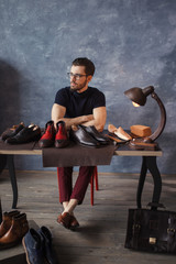 pensive good looking shoeshine man resting after working day. full length photo. job, occupation, big collection of foreign shoes