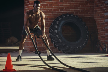 Hard work of Crossfit instructor of African ethnicity proves that training ropes are a very dynamic workout that accelerates athlete's pulse while strengthening his body.