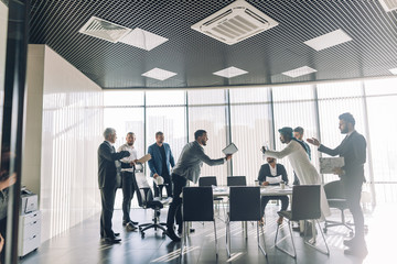 Displeased caucasian boss scolding incompetent employee for bad work results at multiracial group meeting 