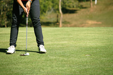 Golfer putting golf ball on the green golf