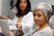 © Cavan Images - Senior woman examining paper materials with woman on background
