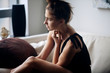 © Cavan Images - Side view of thoughtful young woman sitting on sofa at home
