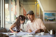 Grandfather And Granddaughter (6-7) Looking At Papers 
