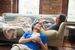 © Cavan Images - Mid adult couple relaxing in modern house interior, lying down, blanket on sofa