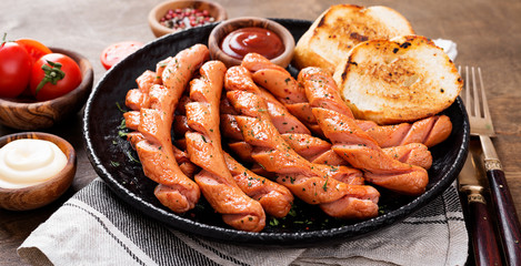 Wall Mural - Grilled sausages and different sauce on a dark wooden background.