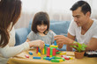 © linghaa - Family time Daughter laughing enjoying playing with her parent on the table in front of sofa at home.