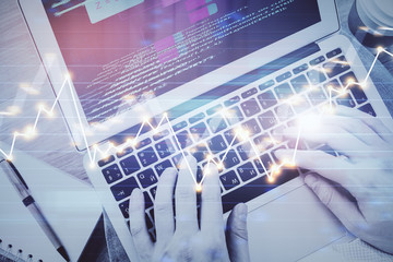 Hands typing on laptop. Business and Financial concept. Double exposure of stock market charts.