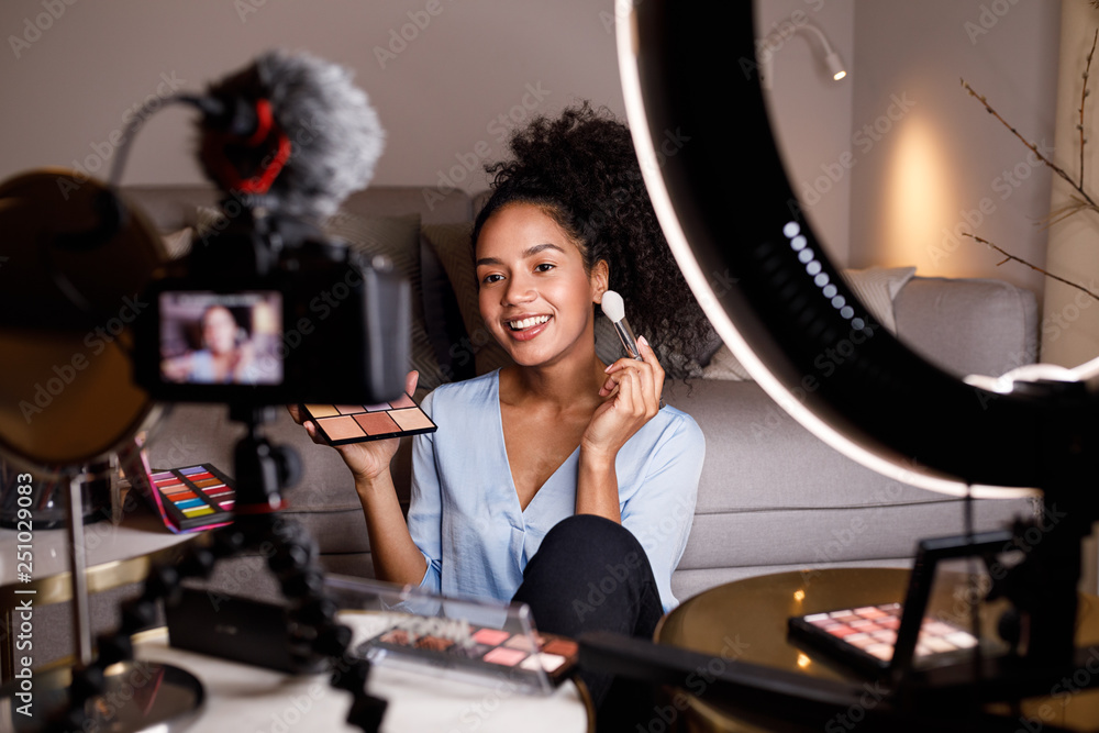 Beauty vlogger making a video tutorial on makeup in living room - obrazy, fototapety, plakaty 