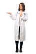 © luismolinero - A full-length shot of a Young doctor woman holding copyspace imaginary on the palm to insert an ad over isolated white background