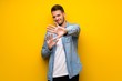 © luismolinero - Handsome man over yellow wall nervous and scared stretching hands to the front