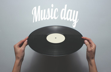 Wall Mural - Music day. Female hands rotate retro vinyl record on a gray background. Top view, minimalism..