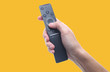 © splitov27 - Hand holds tv remote isolated on yellow background