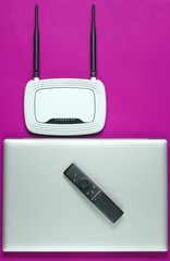 Wi fi router, laptop, pc mouse, remote controller on pink background. Top view.