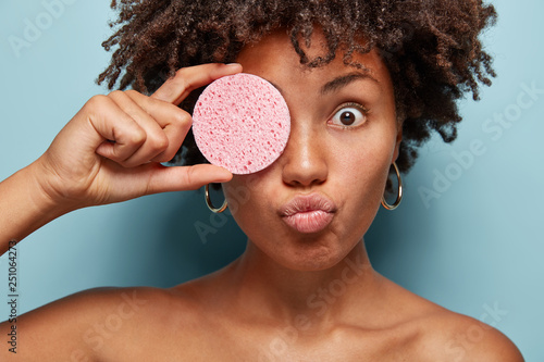 Headshot Of Surprised Black Woman Exfoliates Skin Keeps Sponge On
