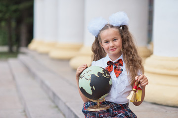 Portrait of beautiful young first-grader Farewell Bell. day of knowledge. beginning of the school year. school equipment. Young girl exploring the globe.