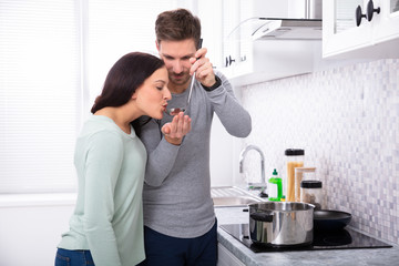 Smiling Man Tasting Food To His Wife