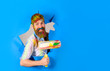 © Svitlana - Repair. Professional painter in protective helmet making hole in paper wall. Happy painter man. Painter with painting roller through hole in paper. Handsome bearded worker with paint roller.Copy space