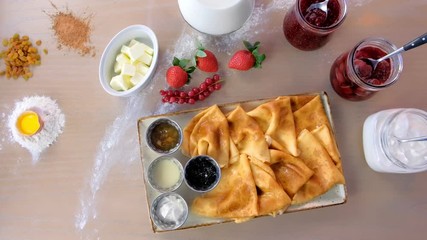 Wall Mural - Russian traditional pancakes, blini served with jams, sour cream, and strawberry on the plate. Close-up top view.