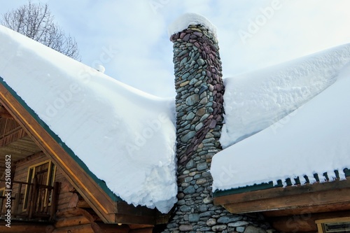 A Closeup View Of A Stone Chimney Attached To A Remote Log Cabin