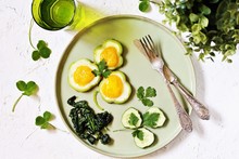 Green Breakfast On St. Patrick's Day. Eggs In The Form Of Clover. Fried Eggs Shamrock  In Green Pepper Rings With Braised Spinach. Parsley Leaves Like Clover Leaves.