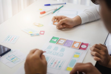 Designer creative graphic discussing sketch planning application mobile phone in office. User experience concept.