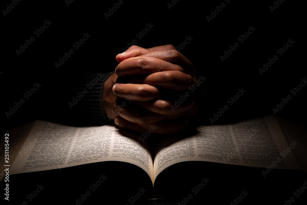 African American Man Praying with Hands on Top of the Bible. - obrazy, fototapety, plakaty 