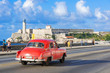 Amerikanischer roter Cabriolet Oldtimer fährt auf dem berühmten Malecon der Festung Castillo de los Tres Reyes del Morro im Hintergrund in Havanna Kuba - Serie Kuba Reportage