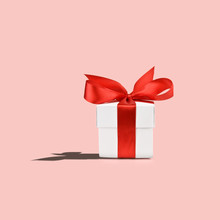 White Gift Box With Red Ribbon On Pink Background