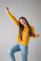 Wall Mural - Happy woman isolated over grey wall background showing winner gesture.