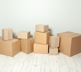 Fototapeta Mapy - Day moving. Delivery of goods, shopping. Cardboard boxes on gray wall background. Copy space for text.